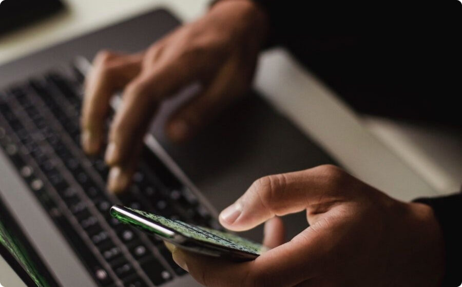 hands typing on laptop with phone